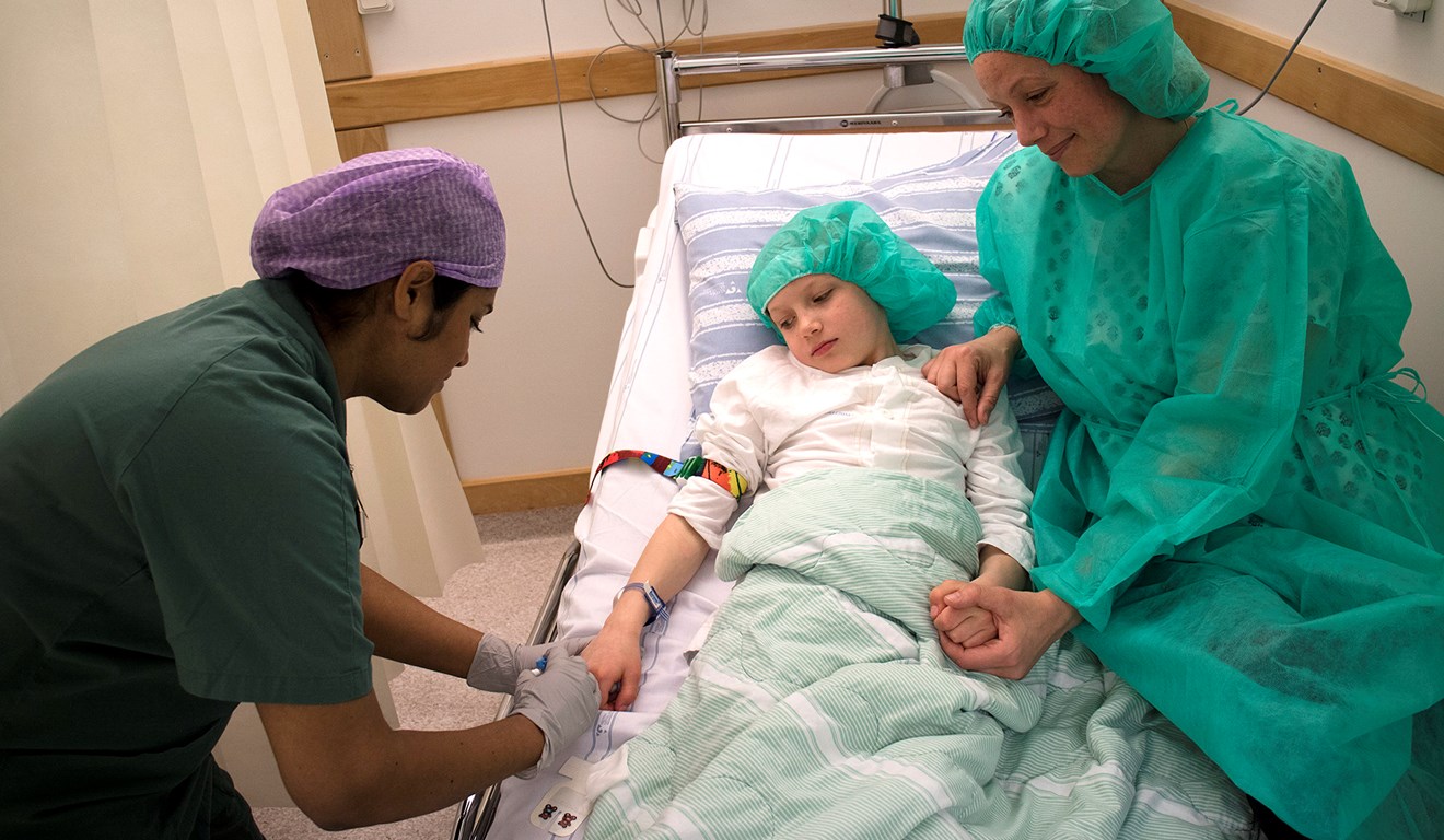 Ett barn med operationskläder får ett stick i handen