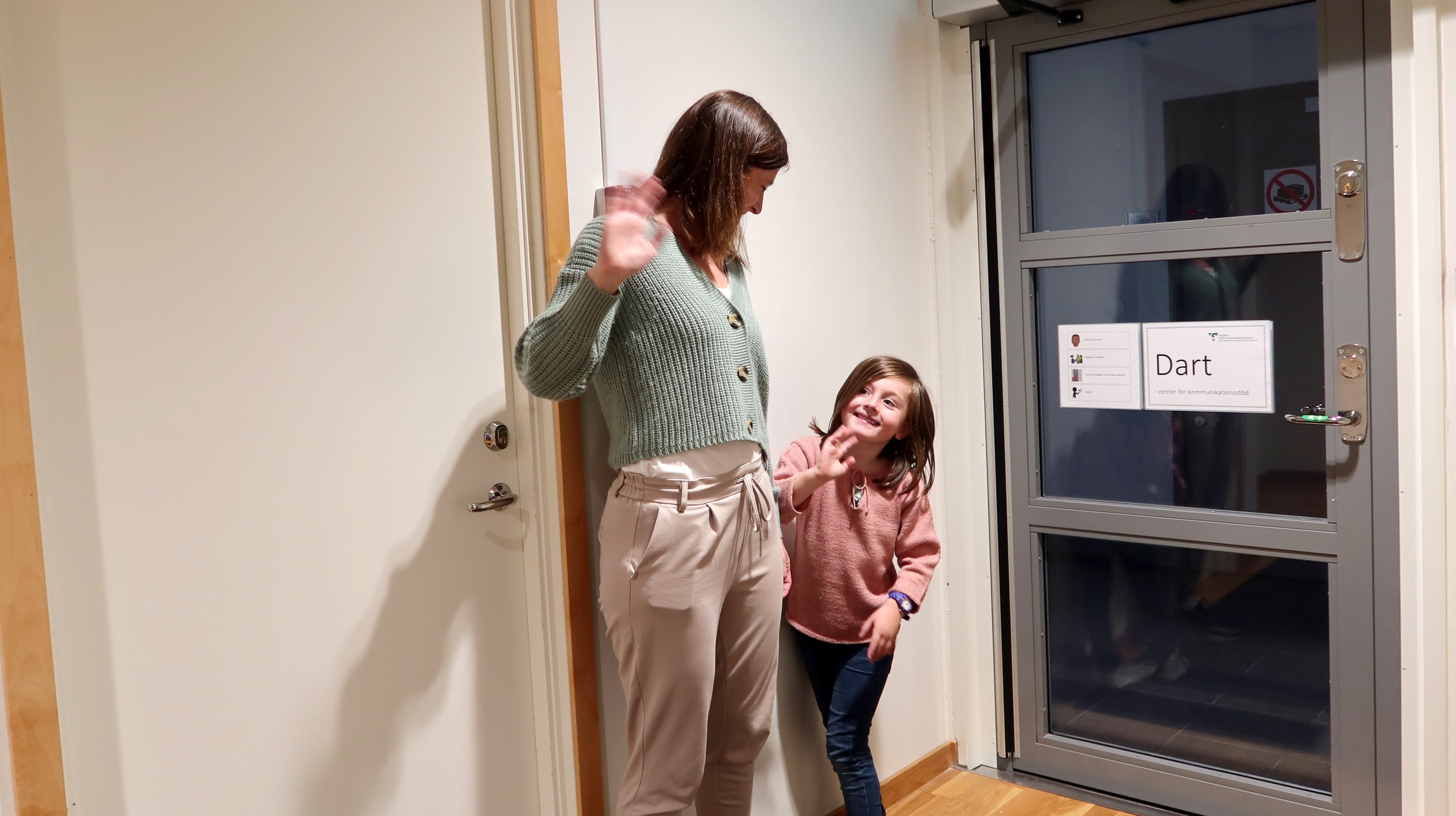 Ett barn och en vuxen vinkar hejdå