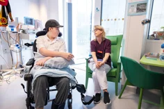 A teenager in a wheelchair talking to the hospitals teacher.