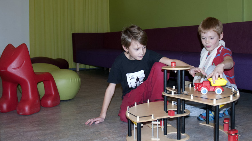 Två barn leker i väntrummet