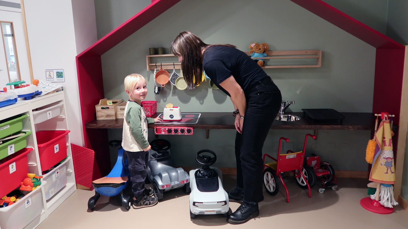 Ett barn och en mamma leker i ett lekrum