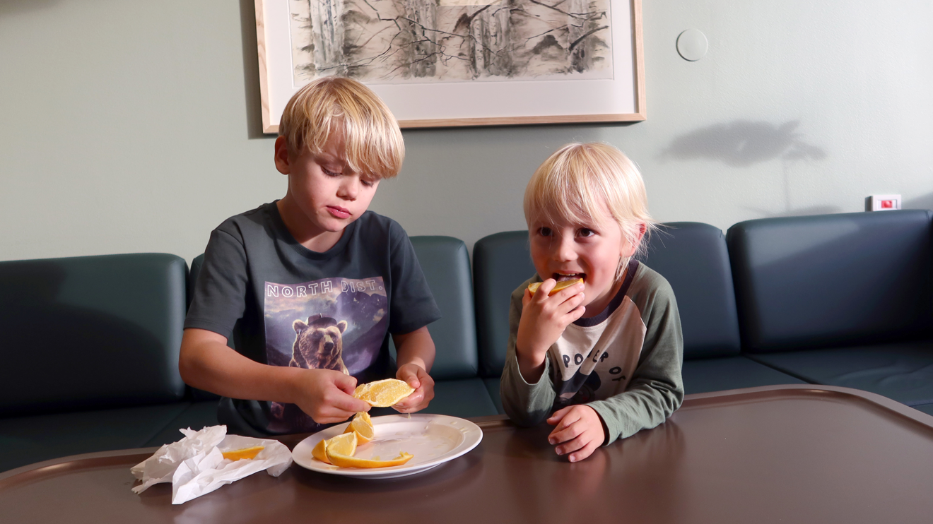 Två barn äter apelsin