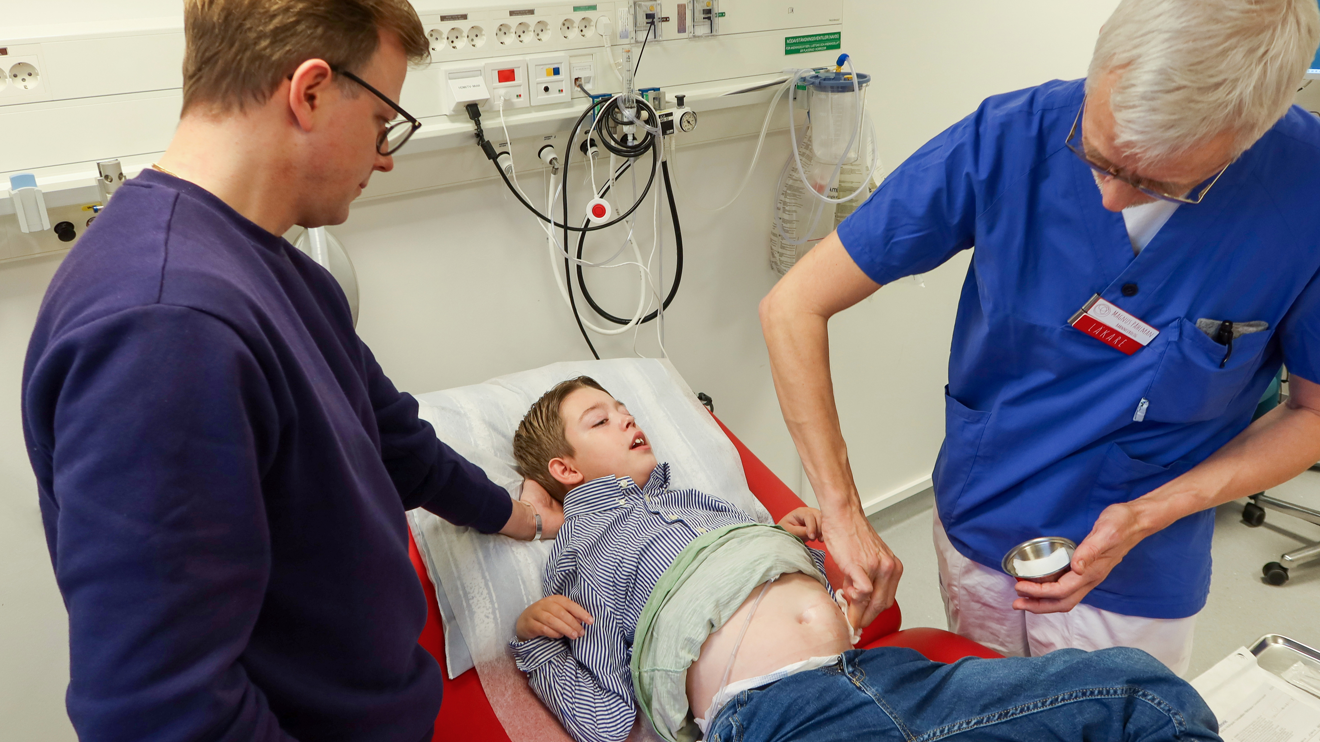 En läkare tvättar en pojke på magen