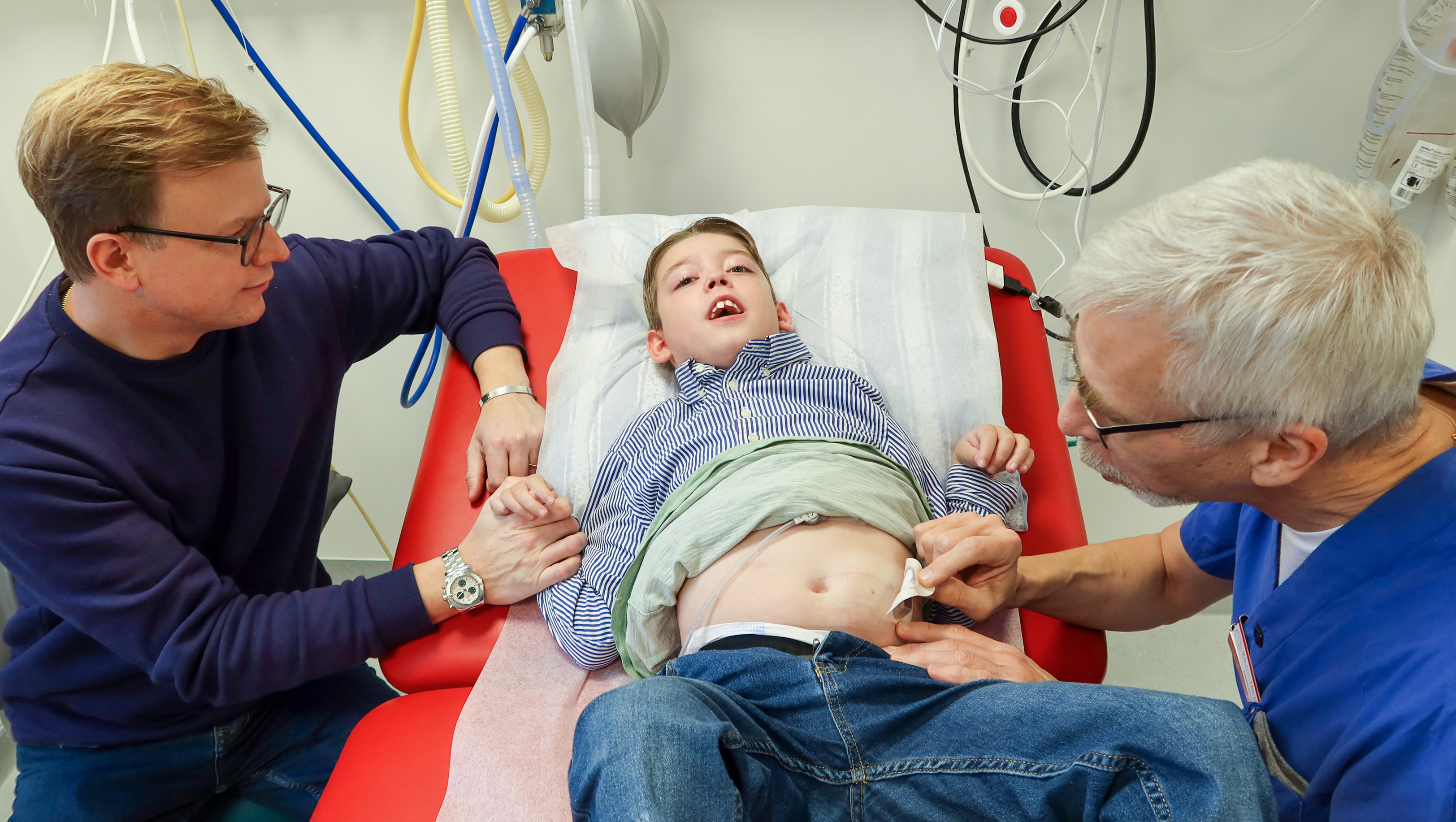 En läkare tar bort ett plåster på en pojkes mage