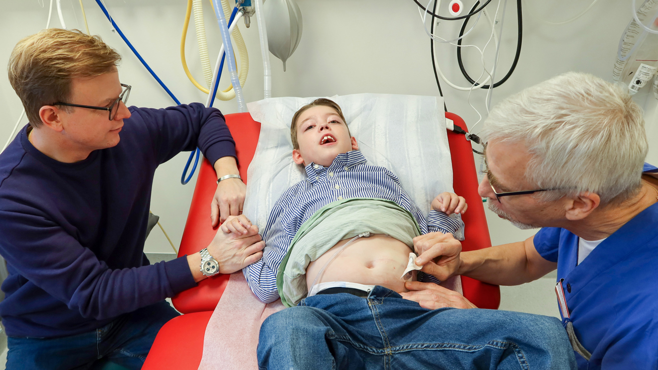 En läkare tar bort ett plåster på en pojkes mage