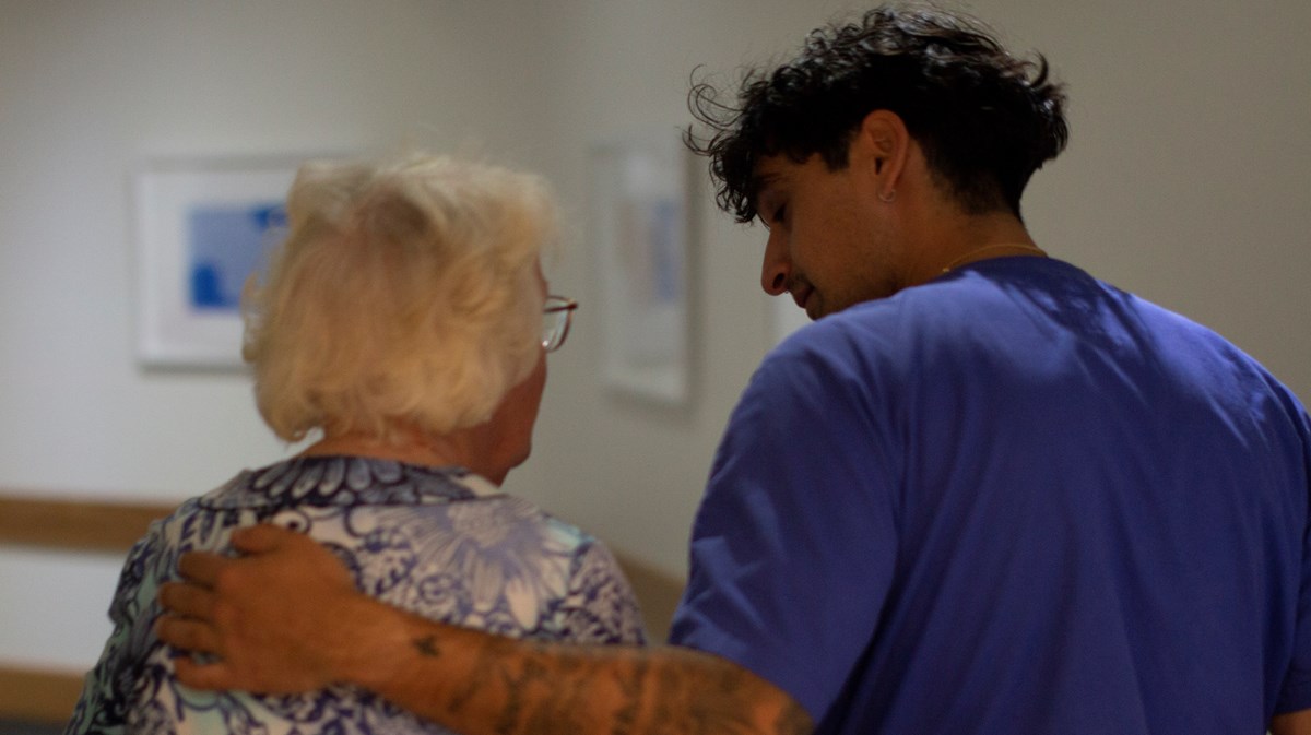 Medarbetaren håller handen om patients axlar