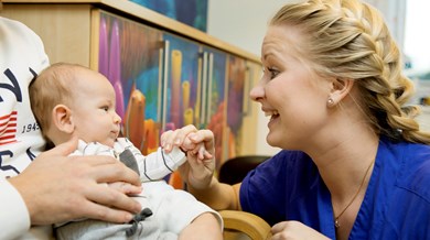 Sjuksköterska ler mot bebis.