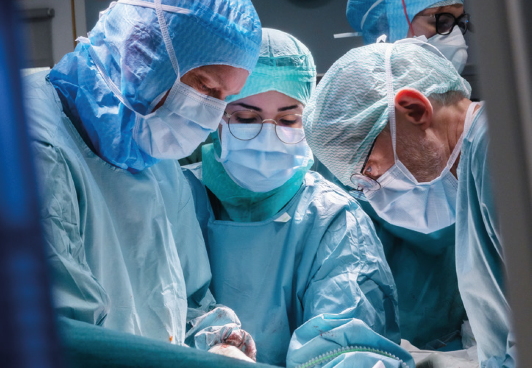  Four healthcare professionals in surgical scrubs performing an operation.