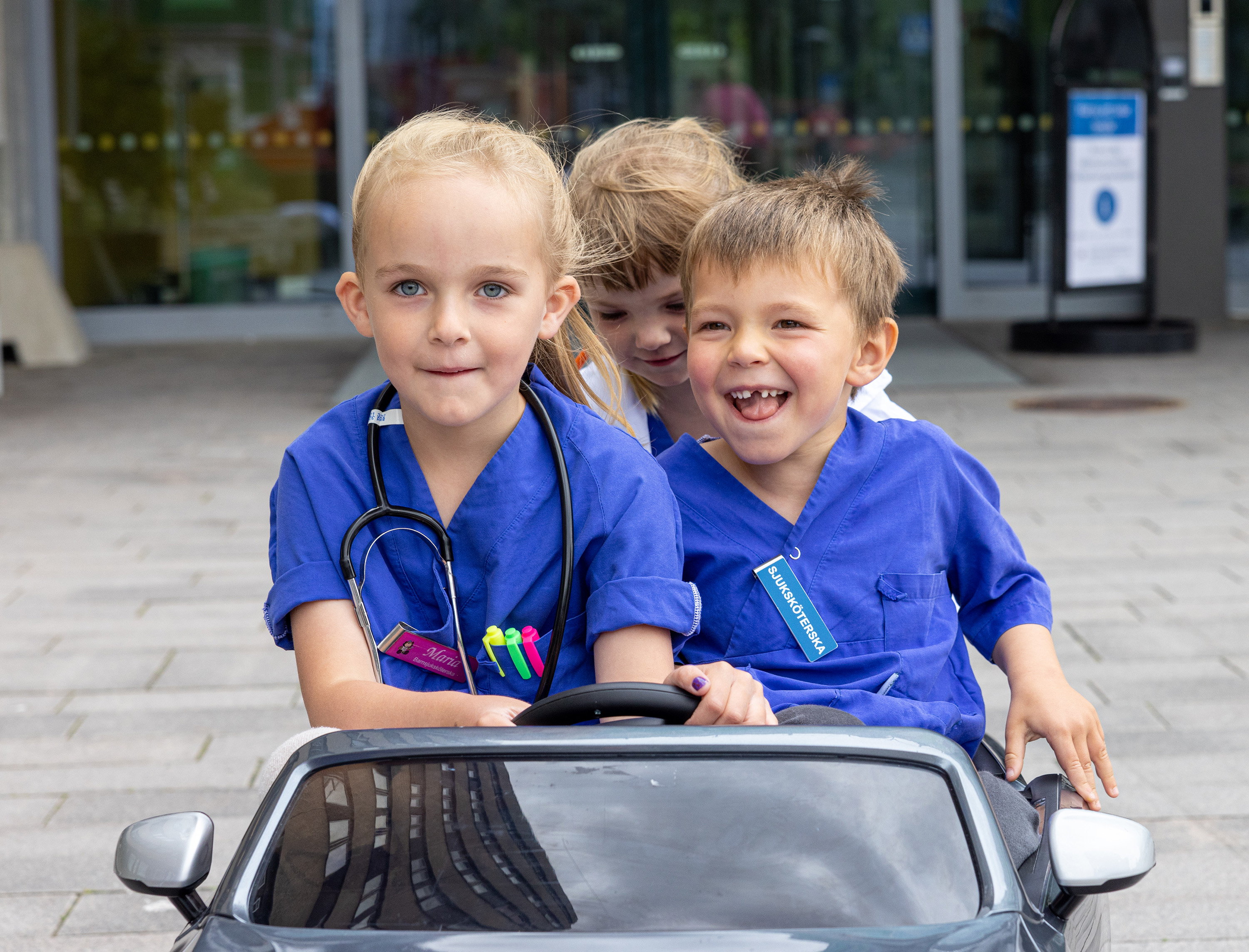 Three children riding in a toy car.