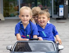 Three children riding in a toy car.