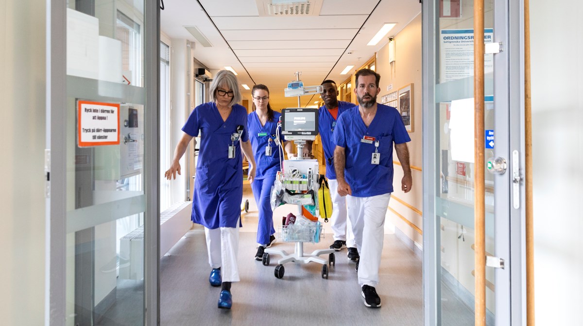 Ett expertteam av läkare och sjuksköterskor går genom sjukhuskorridor med medicinsk utrustning.