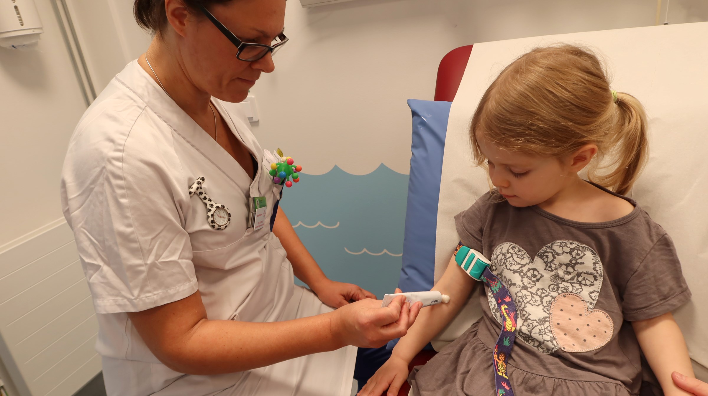 Ett barn får bedövningssalva i armvecket