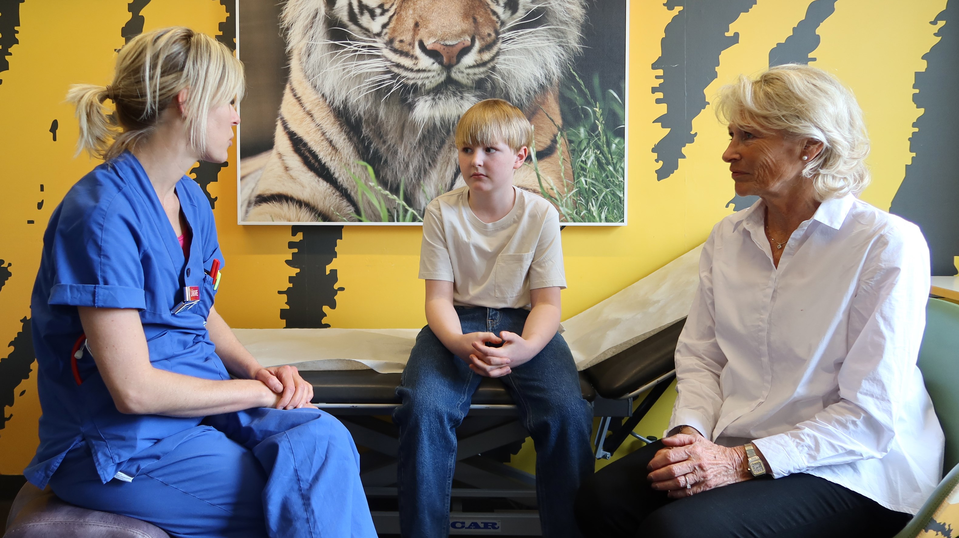En doktor pratar med ett barn och en mormor