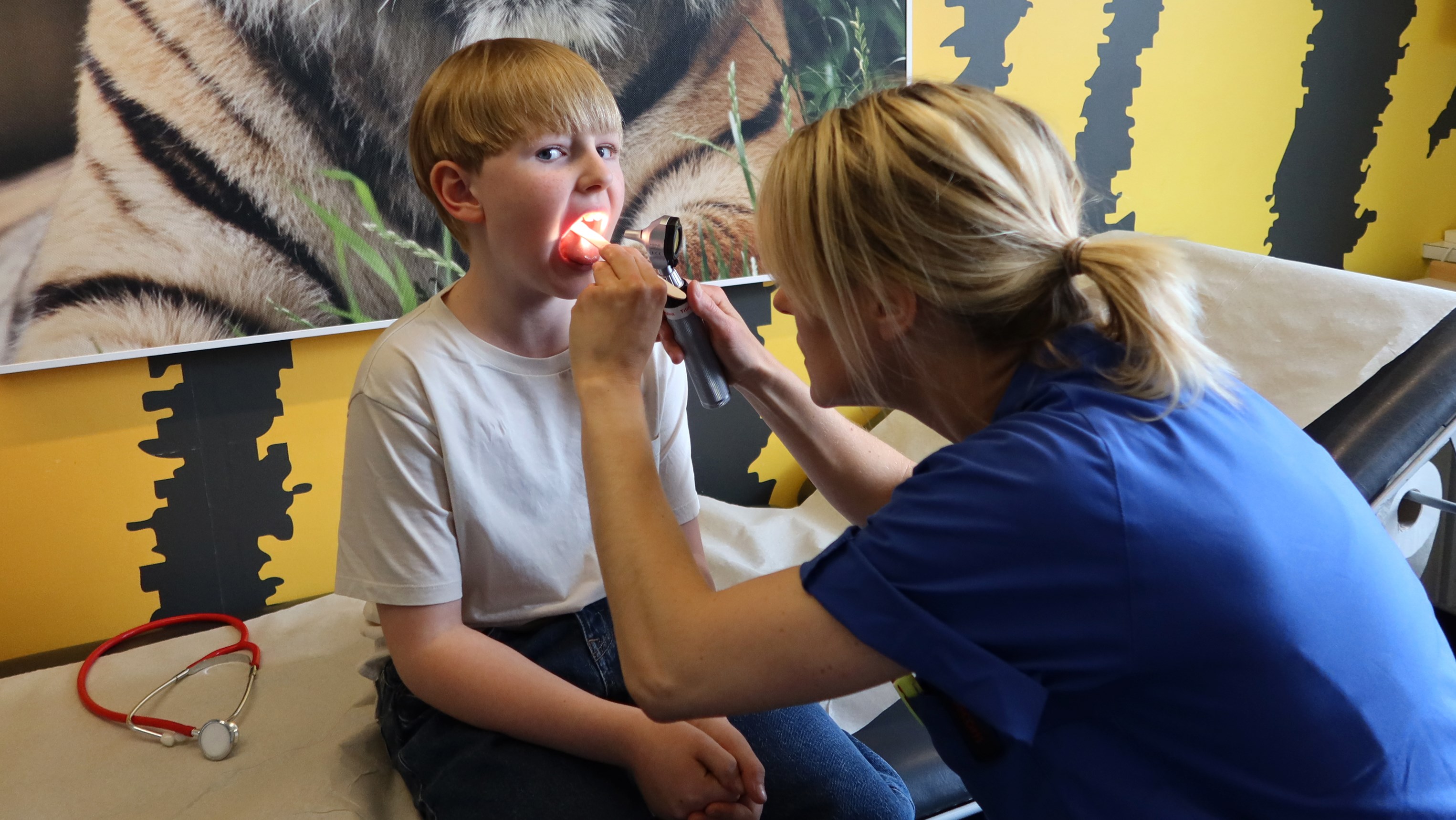 En doktor tittar i halsen på ett barn