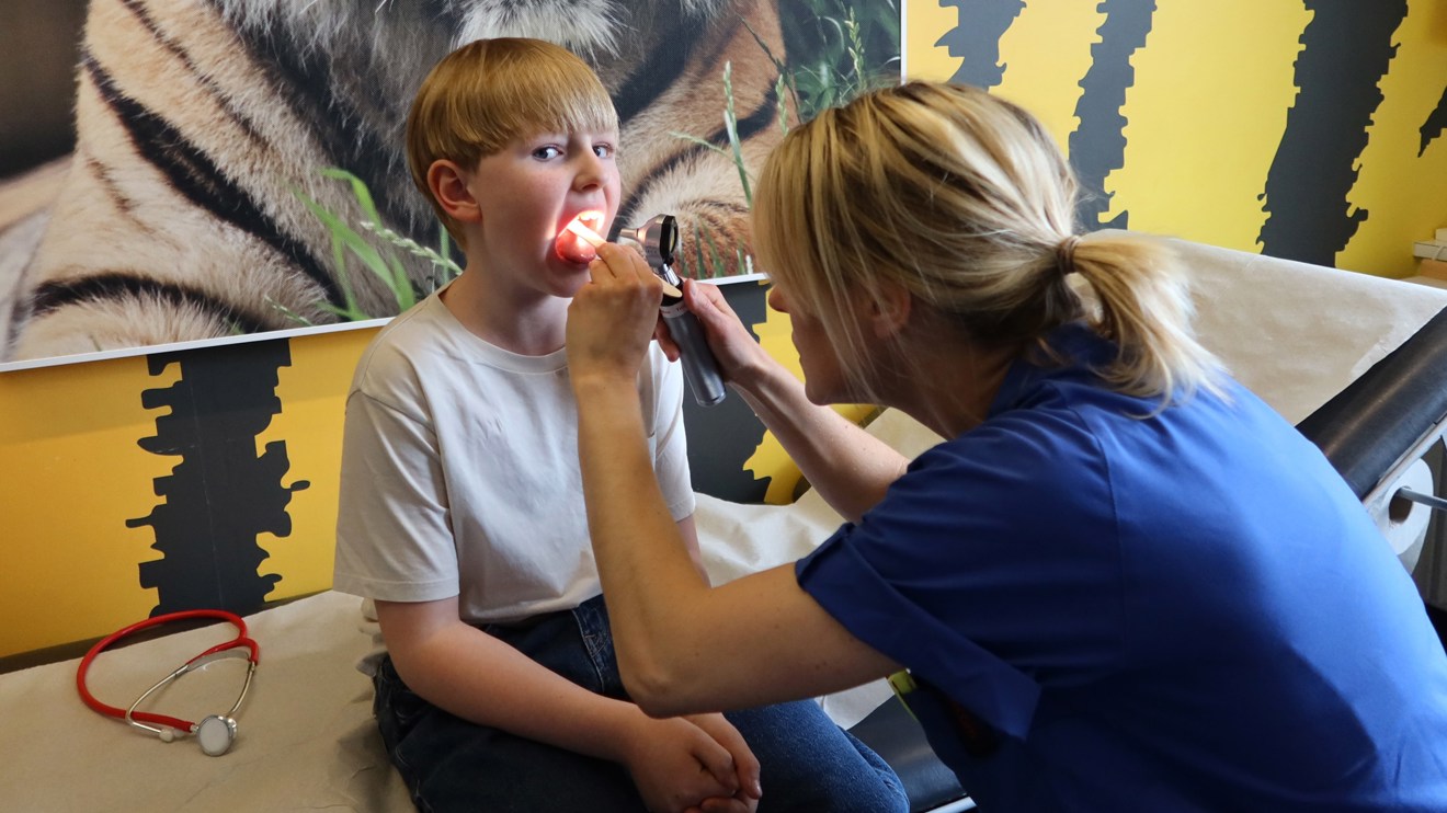 En doktor tittar i halsen på ett barn