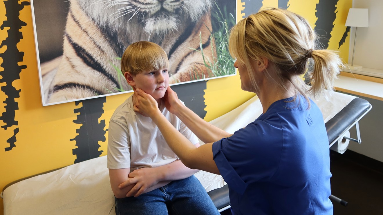 En doktor känner på halsen på ett barn