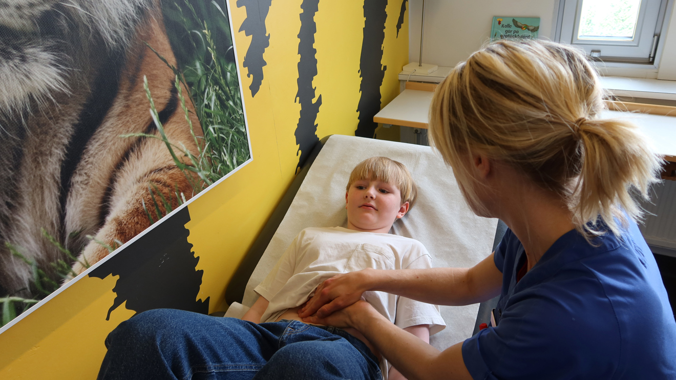 En doktor känner på magen på ett barn