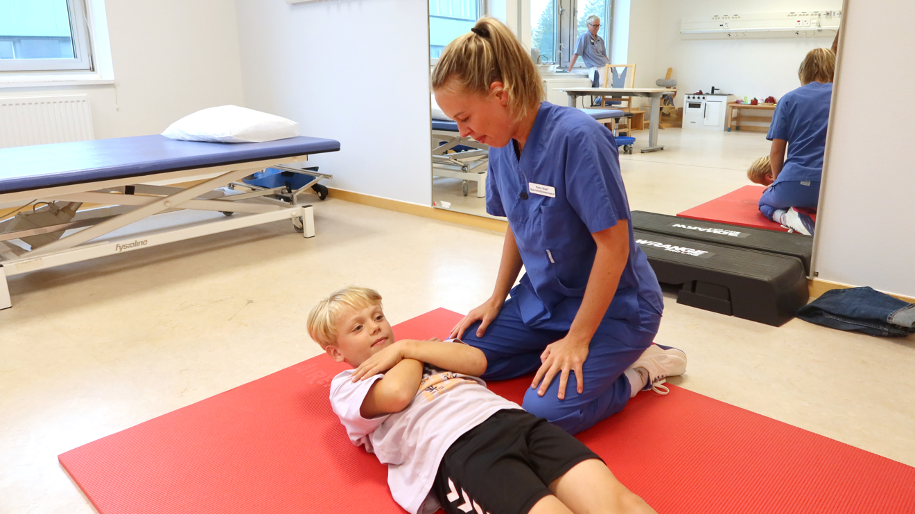 Ett barn ligger på en matta och lyfter överkroppen