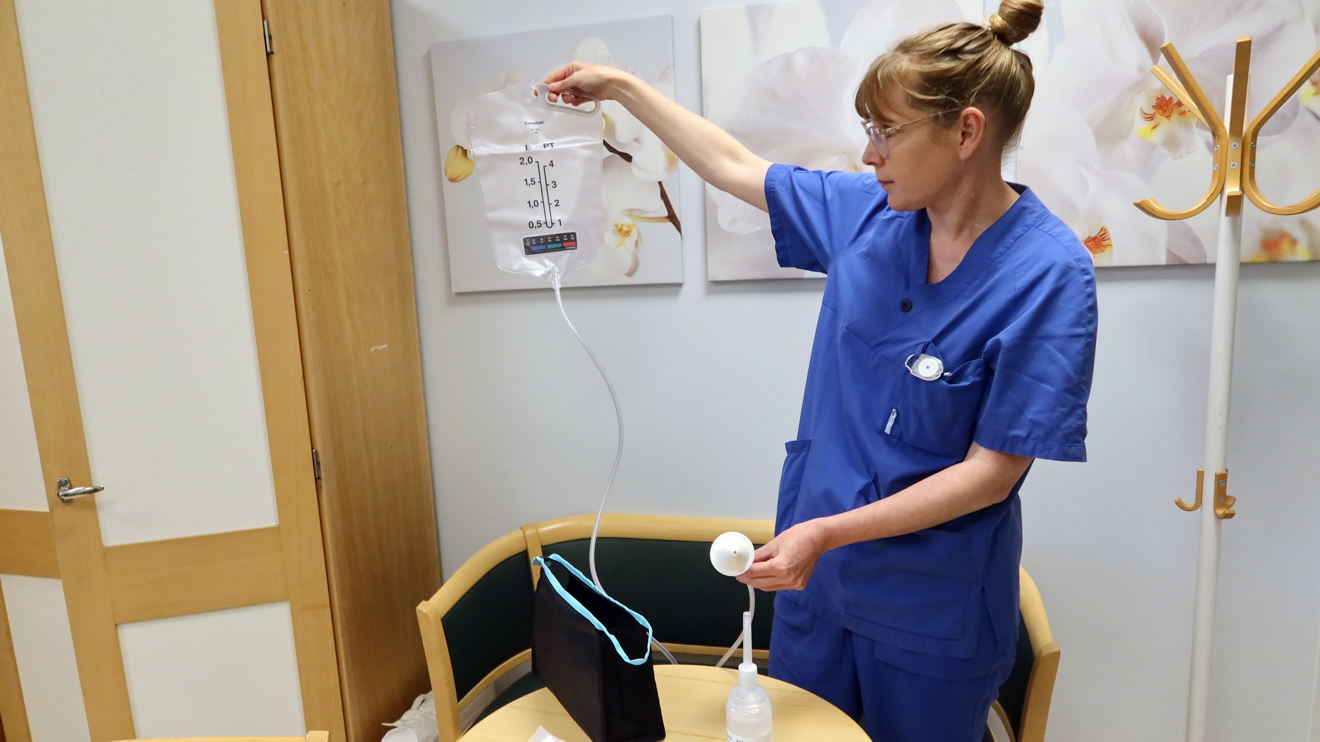 En uroterapeut visar en påse med en slang