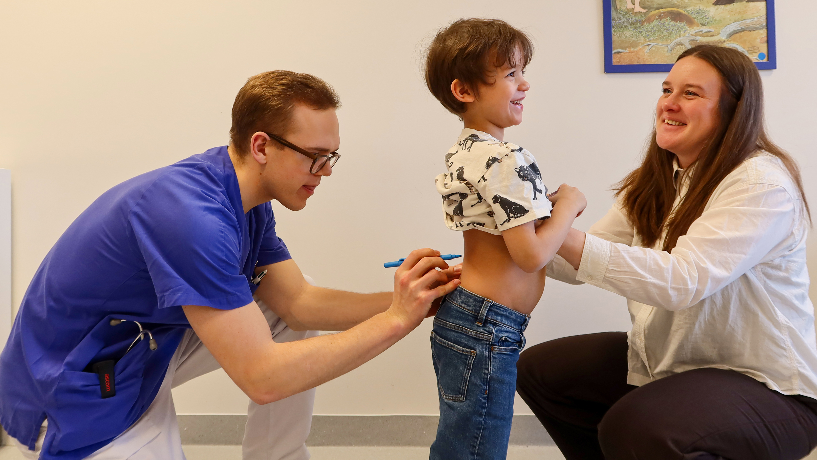 En doktor ritar på ryggen på ett barn