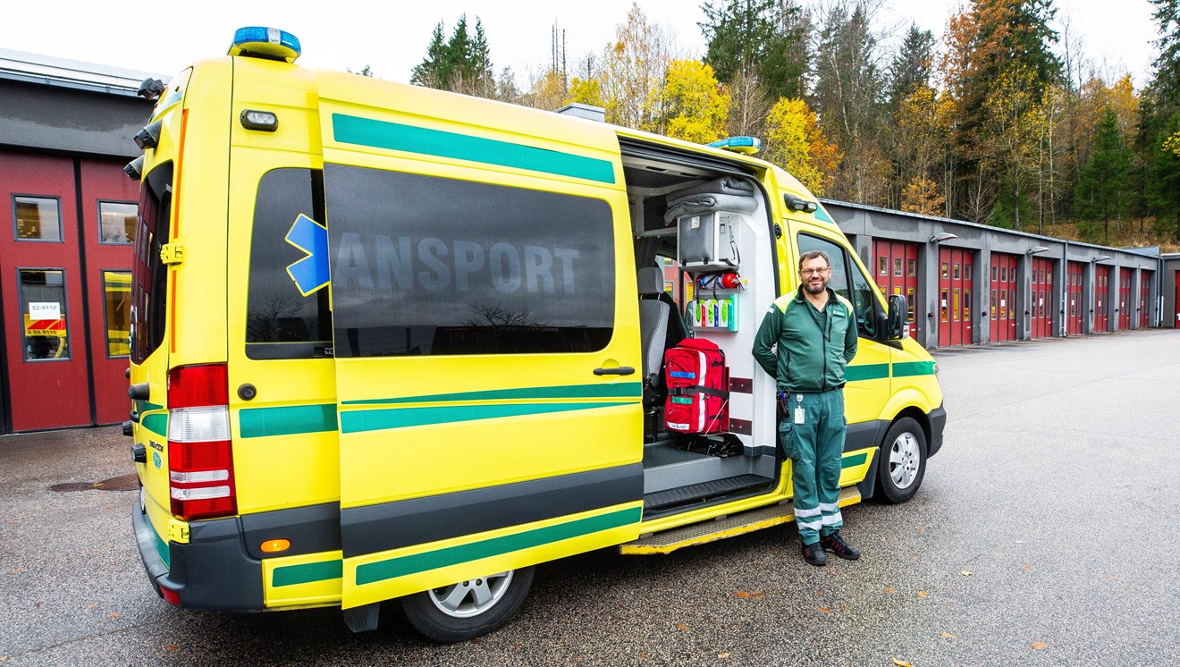 Gul ambulans och grön personal framför