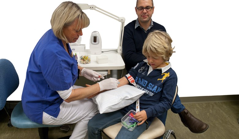 Ett barn tar ett blodprov och tittar i presentlådan