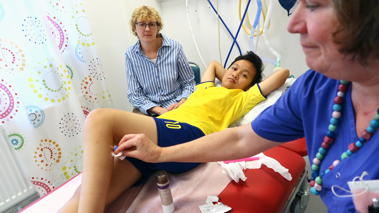 En sjuksköterska tar bort klisterlappar på ett barn