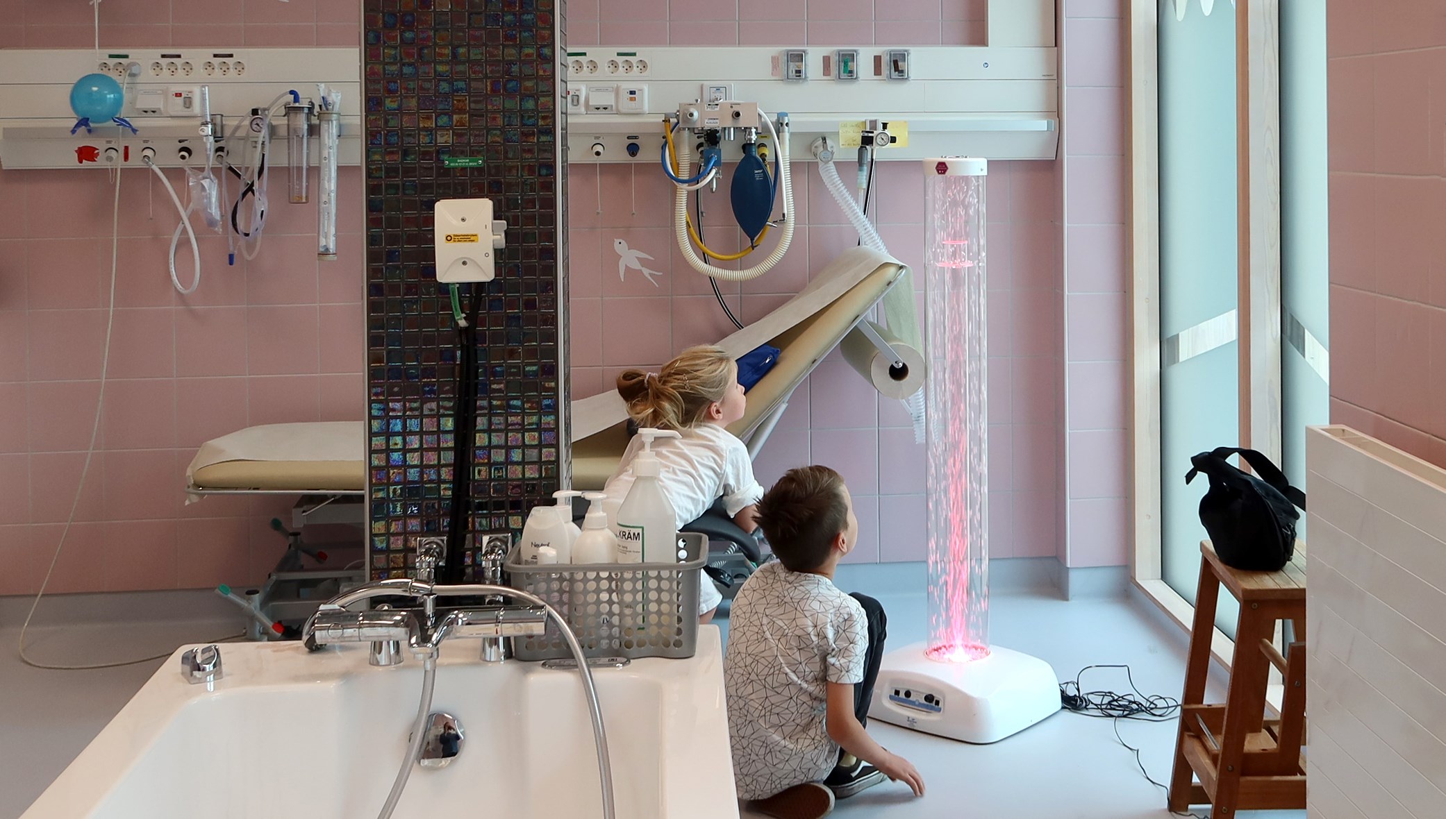 Ett stort badrum. Två barn framför en lampa.