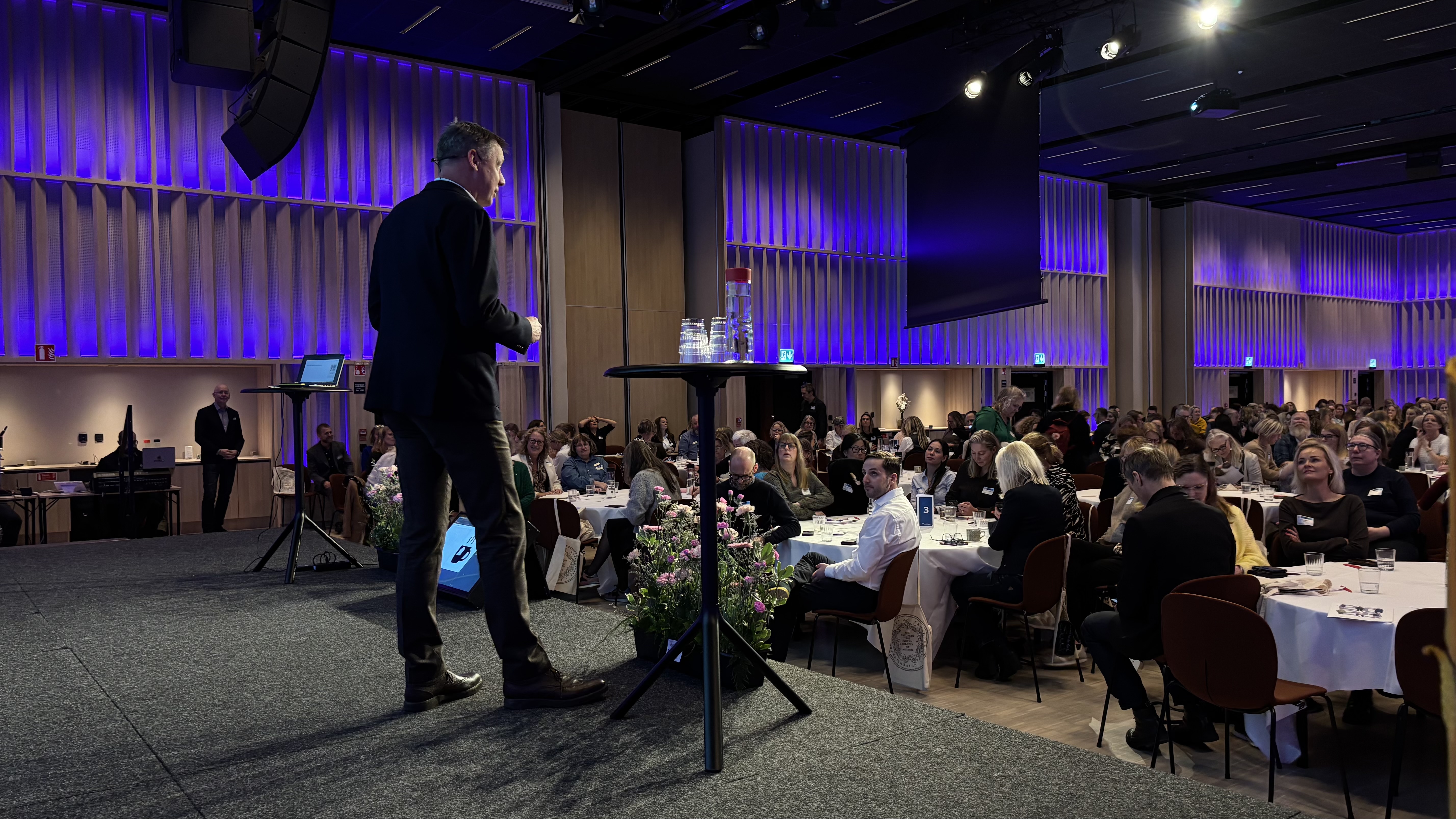 Kostyklädd man på scen framför publik.