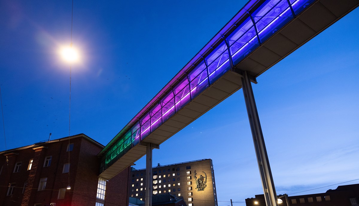 Upplyst gångbro vid Sahlgrenska sjukhuset. Bron lyser i grönt, rosa och blått och lystes upp i samband med Sällsynta dagen 2022.