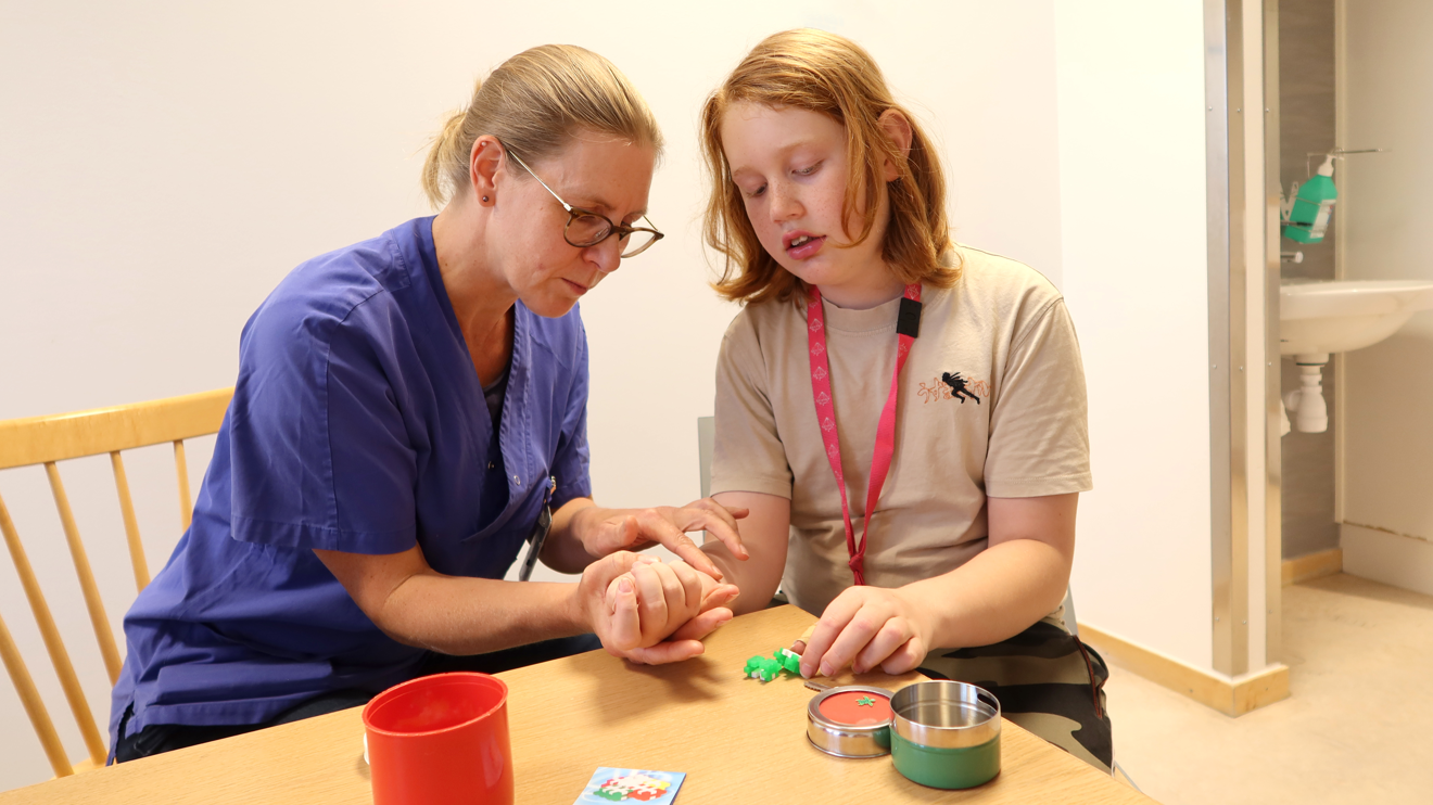 En arbetsterapeut kollar ett ärr i ett barns hand