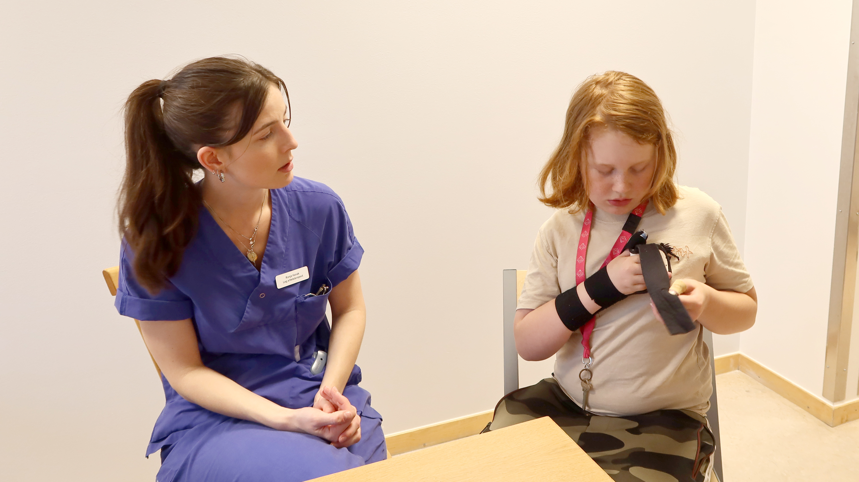 En arbetsterapeut kollar ett barn som tar på sin ortos