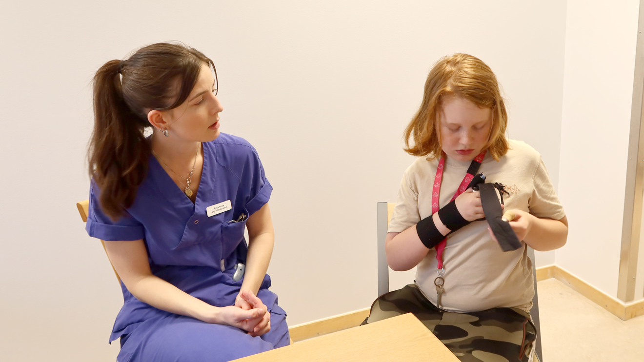 En arbetsterapeut kollar ett barn som tar på sin ortos