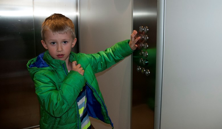 Ett barn trycker på en hissknapp