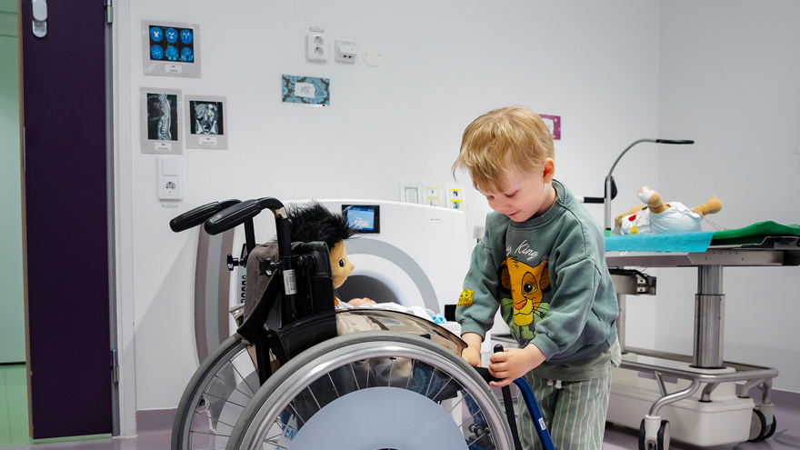 A child playing with a doll in a wheelchair.