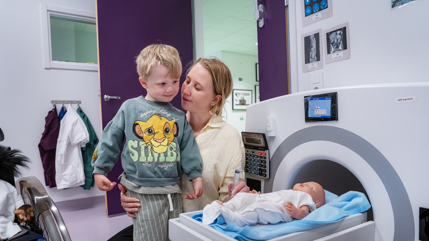 A mother and child with a toy MRI machine.