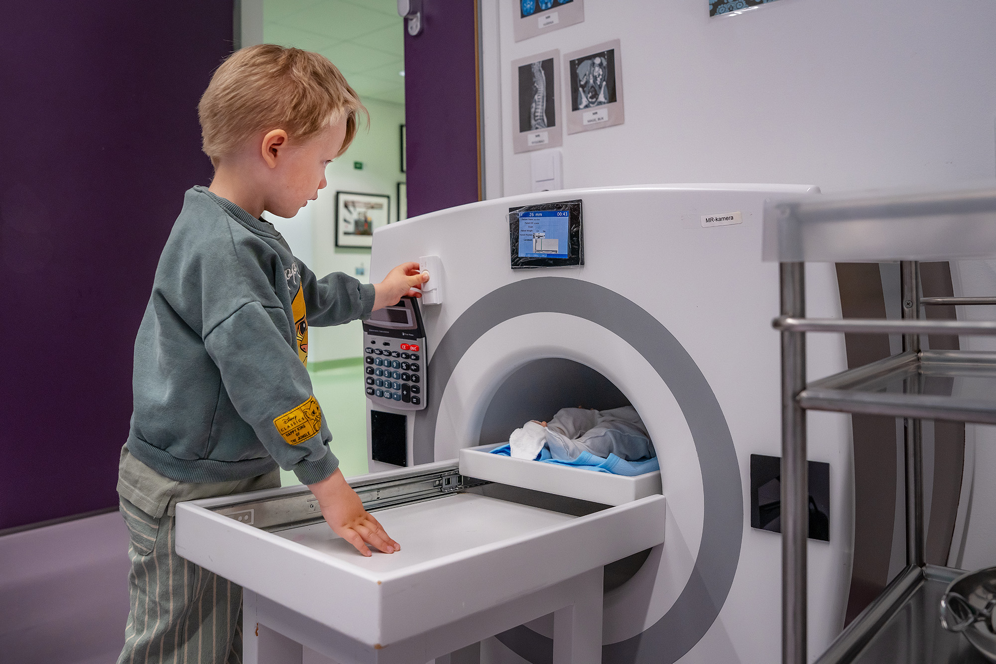 A child playing with a doll in a toy MRI machine.