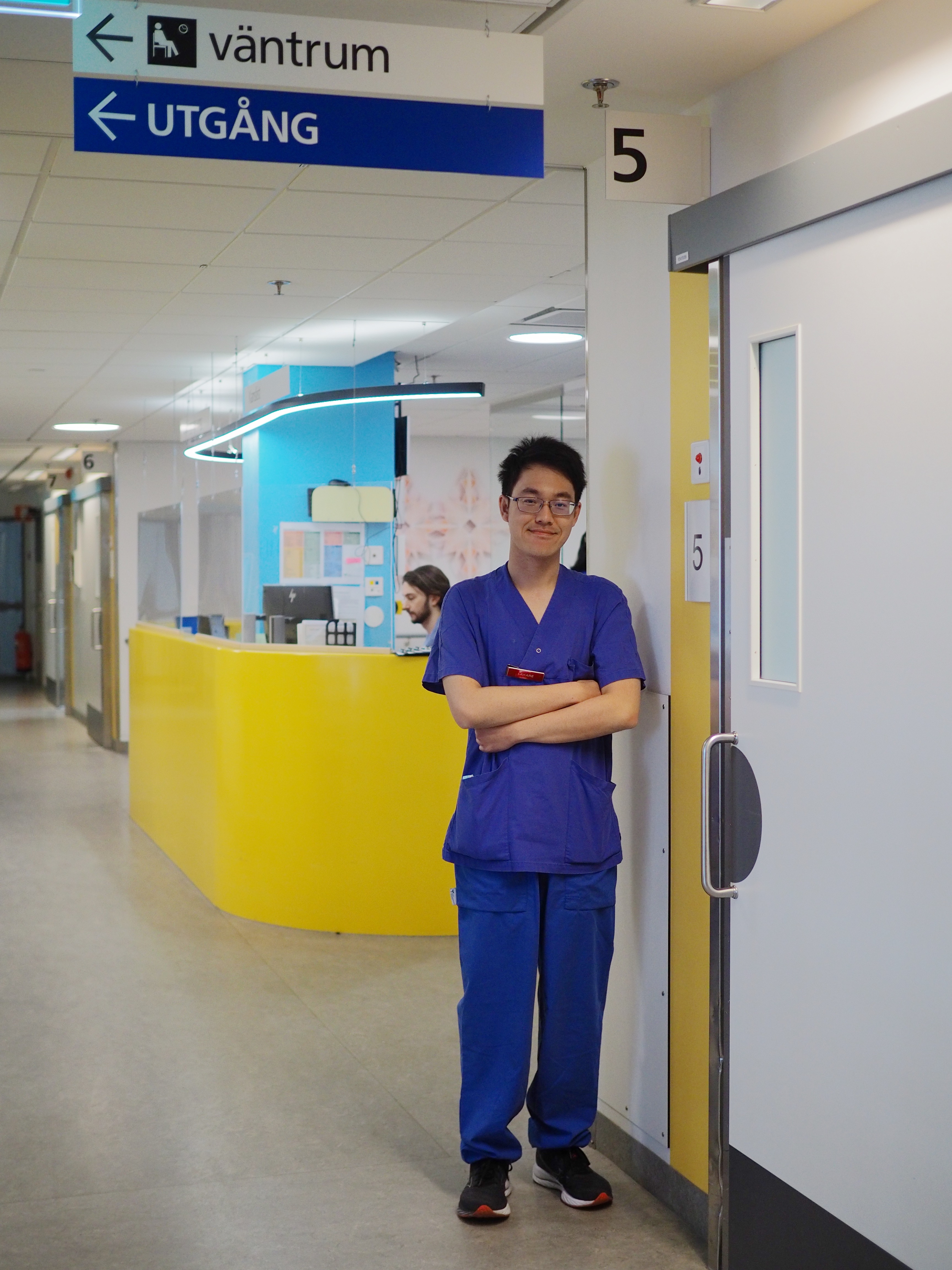 Dr Toon in blue scrubs in front of yellow reception area