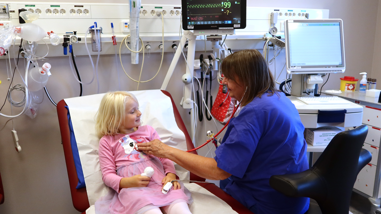 En sköterska lyssnar på hjärtat på ett barn