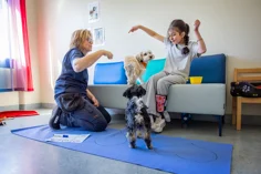 A child and an adult woman playing with two dogs.
