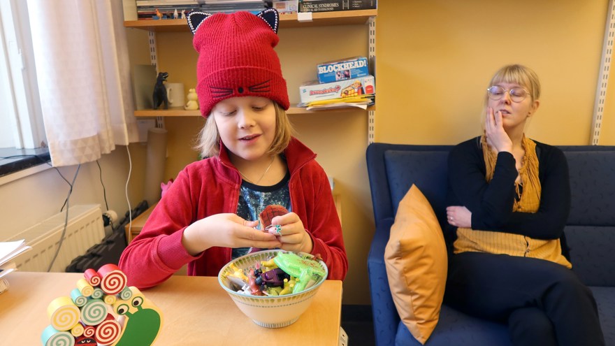 Ett barn väljer en liten leksak ur en skål