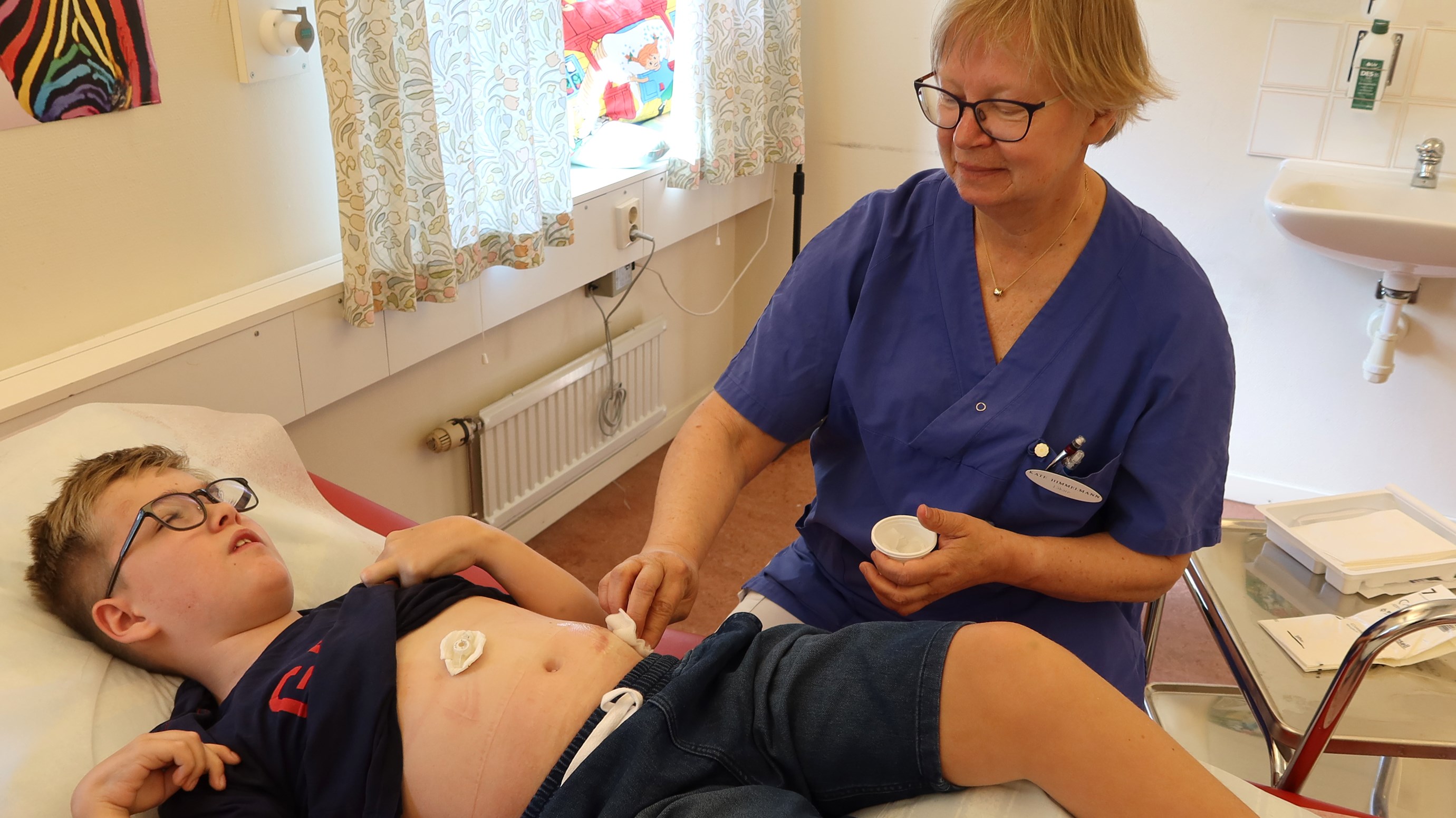 En doktor tvättar ett barn på magen med en tuss