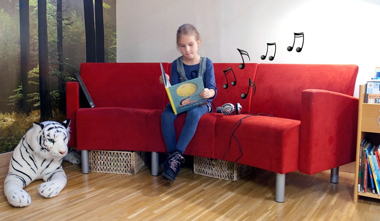 Ett barn läser i en soffa