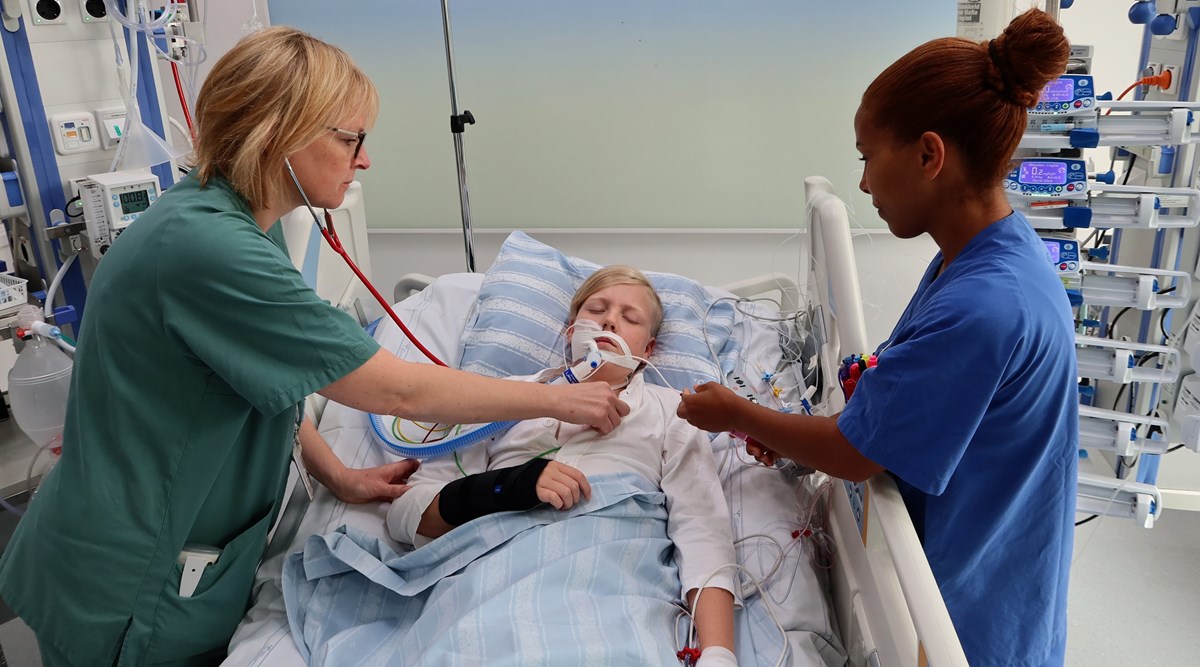 Ett barn i en sjukhussäng. Personal lyssnar på hjärtat och håller i en spruta.