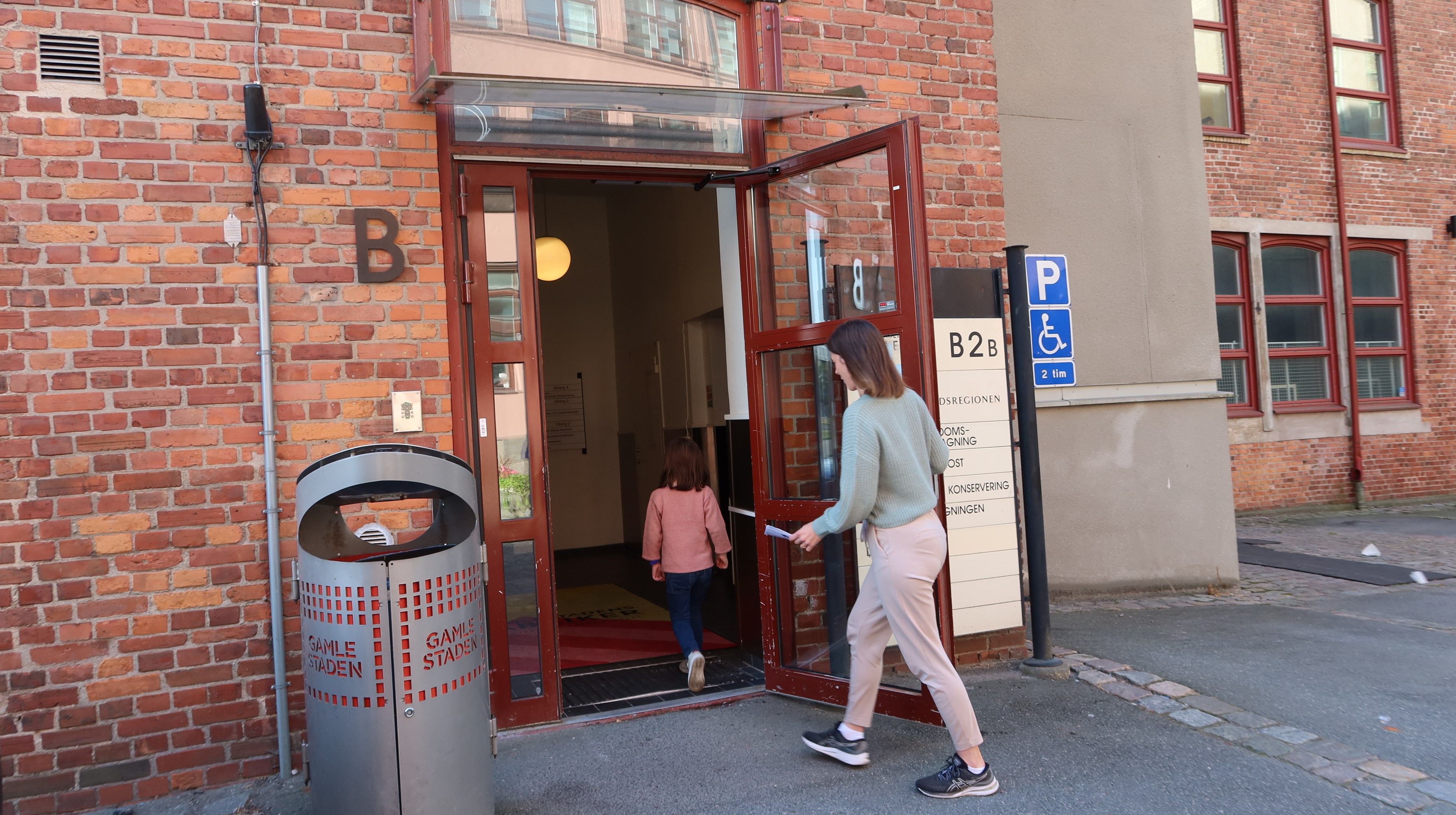 Ett  barn och en vuxen på väg in genom em dörr