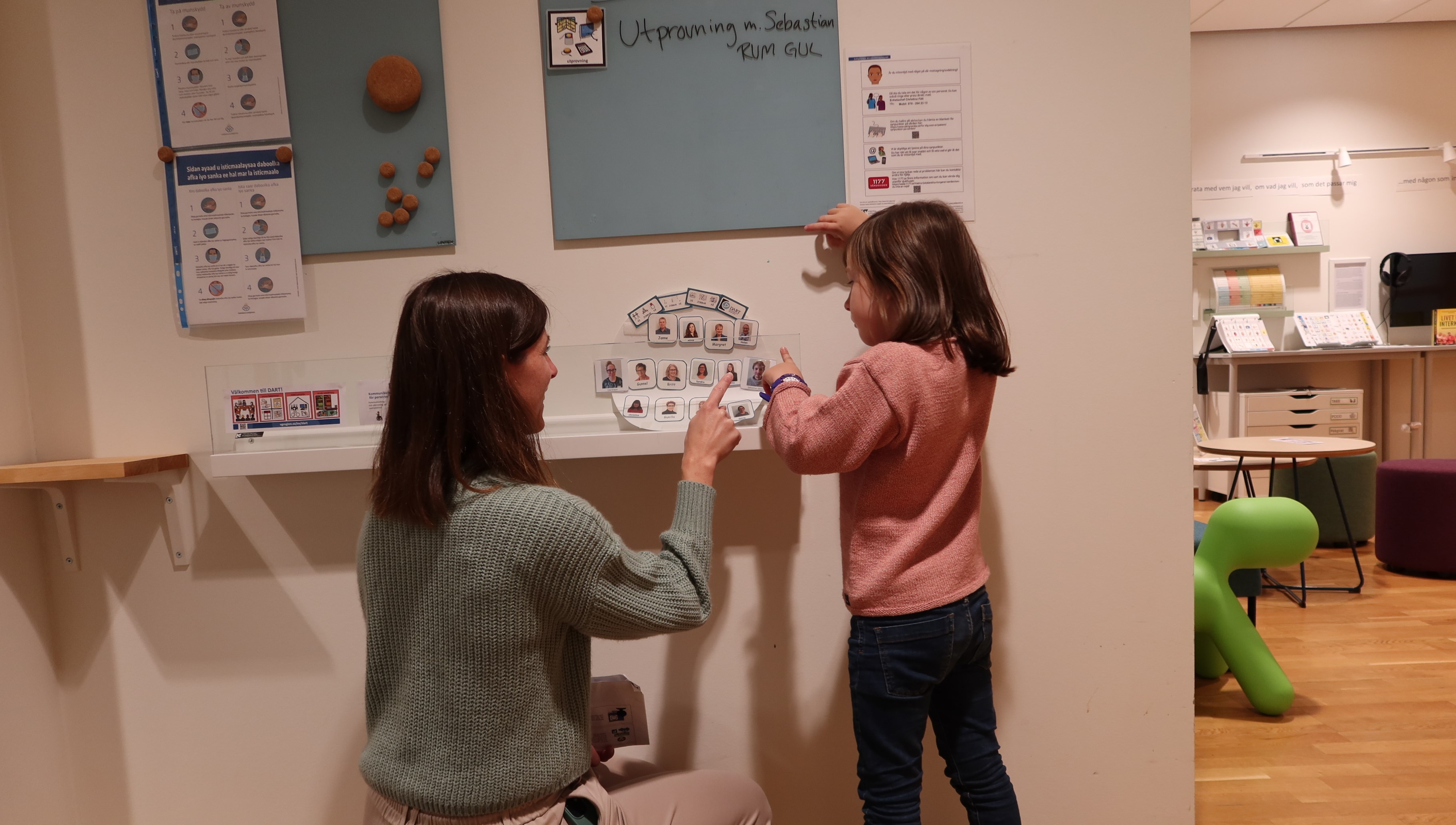 Ett barn och en vuxen pekar på bilder av de som jobbar här