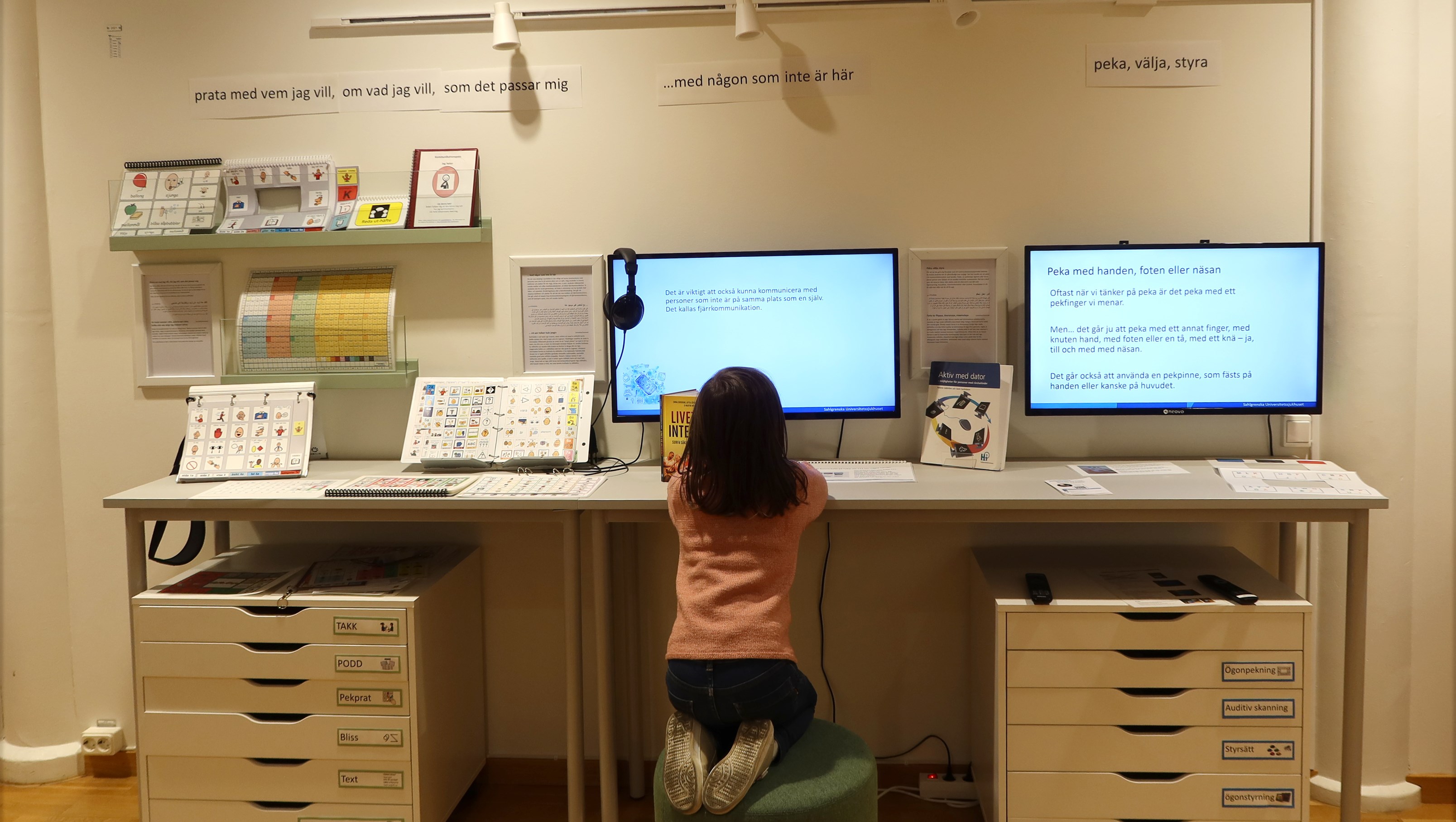 Ett barn sitter på en pall framför datorer