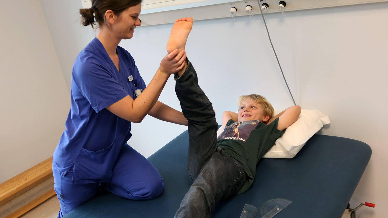 En sjukgymnast lyfter benet på ett barn