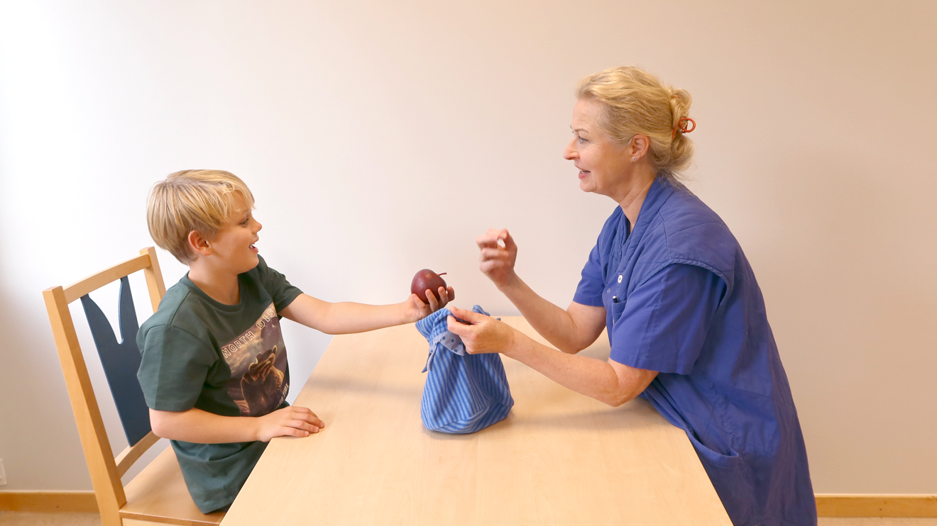 Ett barn plockar upp ett äpple ur en påse