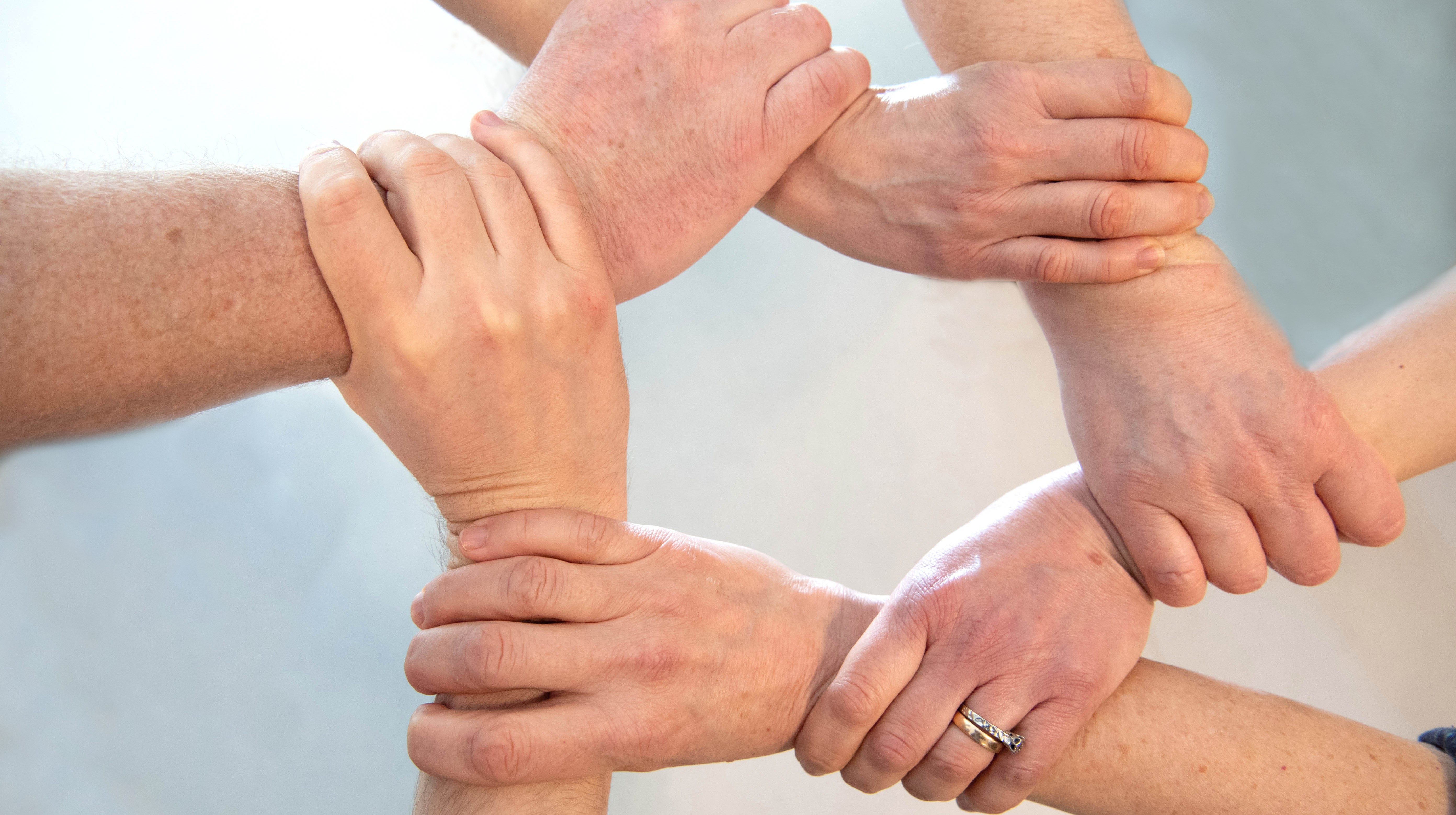Flera händer som håller i varandra i en ring
